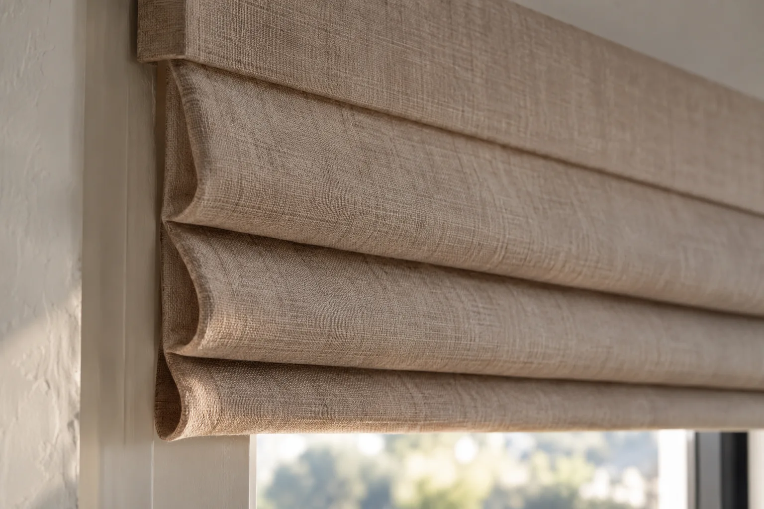 Close side view of linen Roman shade folds stacking beneath a covered headrail