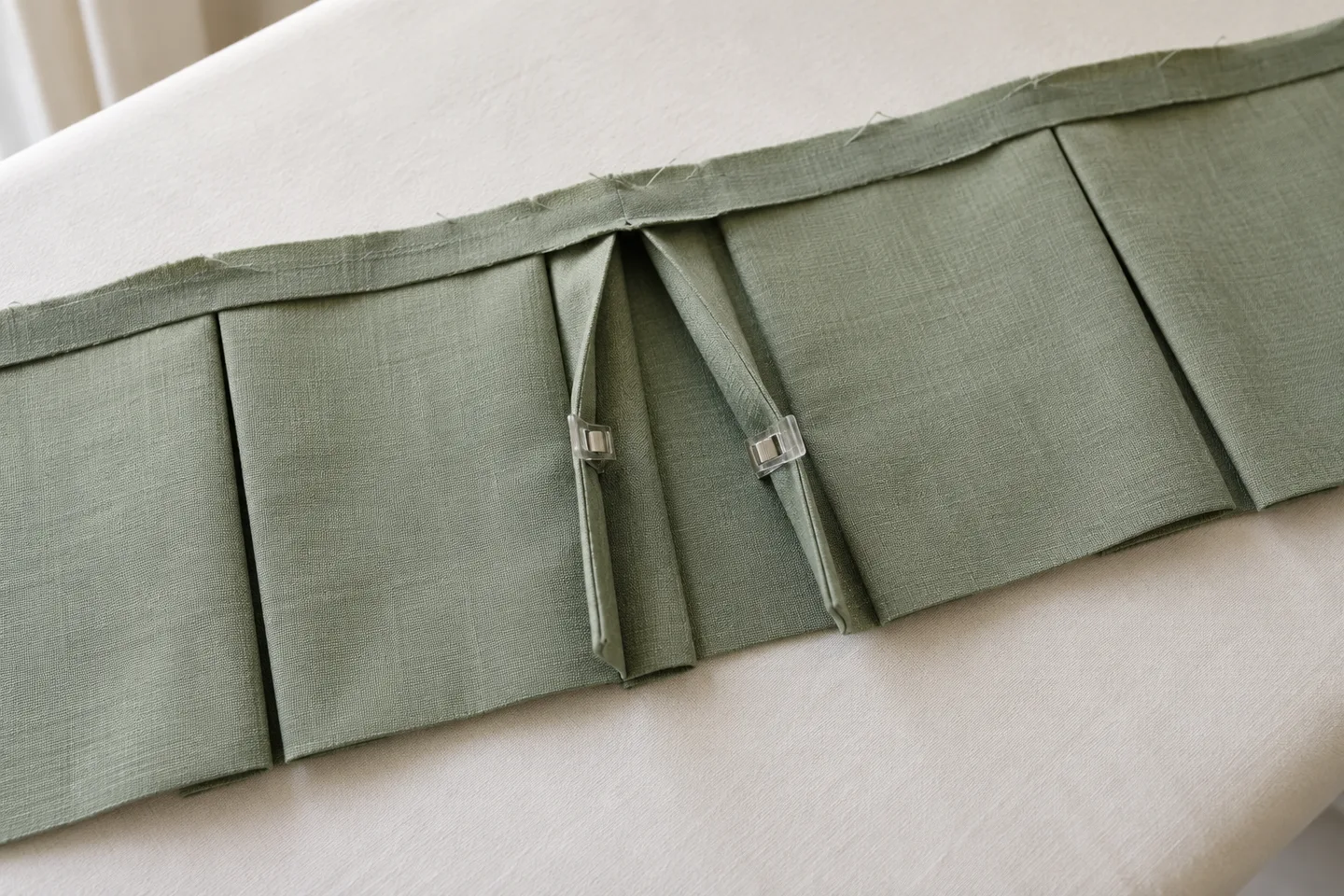 Sage valance fabric opened at the back to show an inverted box pleat with sewing clips